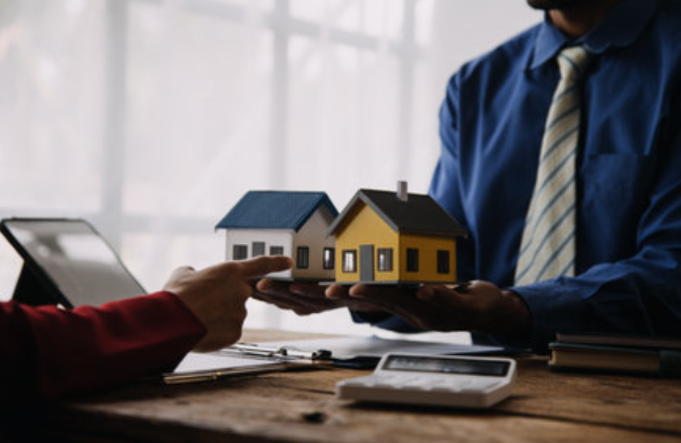 Two people holding up a model of houses